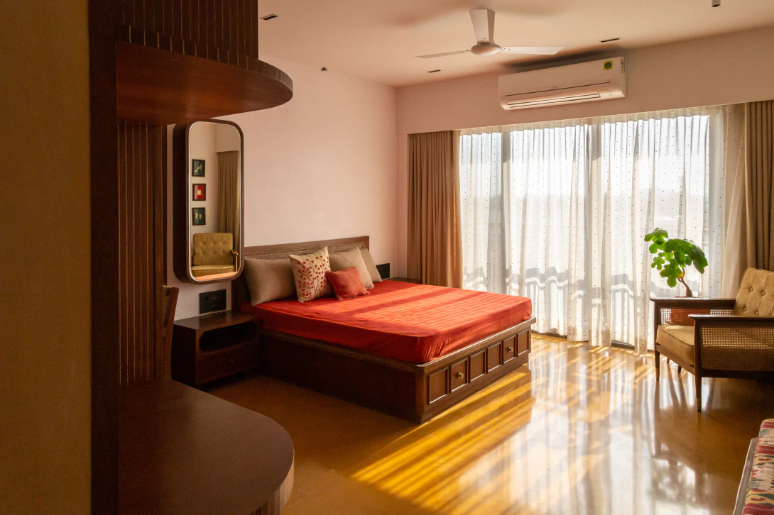 Alankāra sunlit bedroom suite with bespoke wooden bed, curved study table, and polished stone flooring