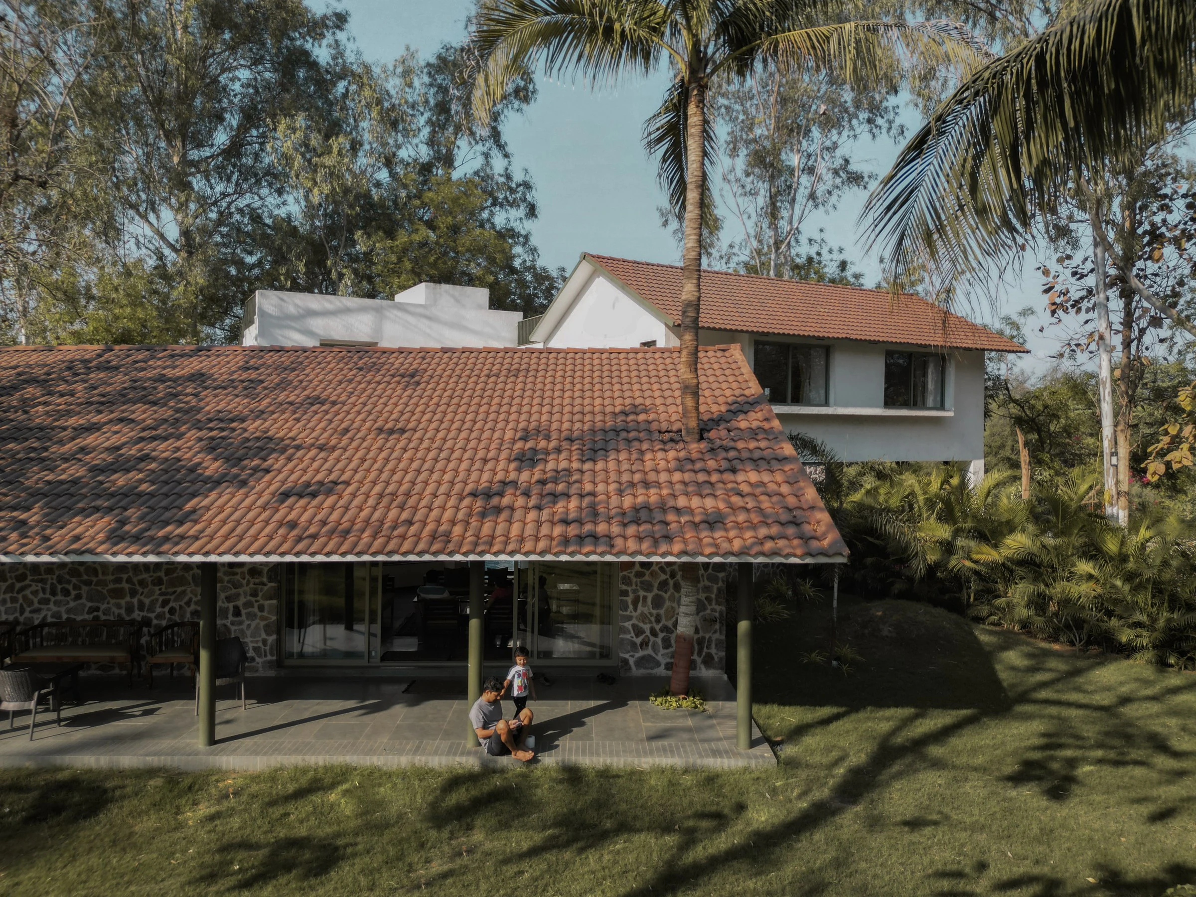 Aerial view of Asarma showing tiled roofs, central courtyard pool, and family on the verandah