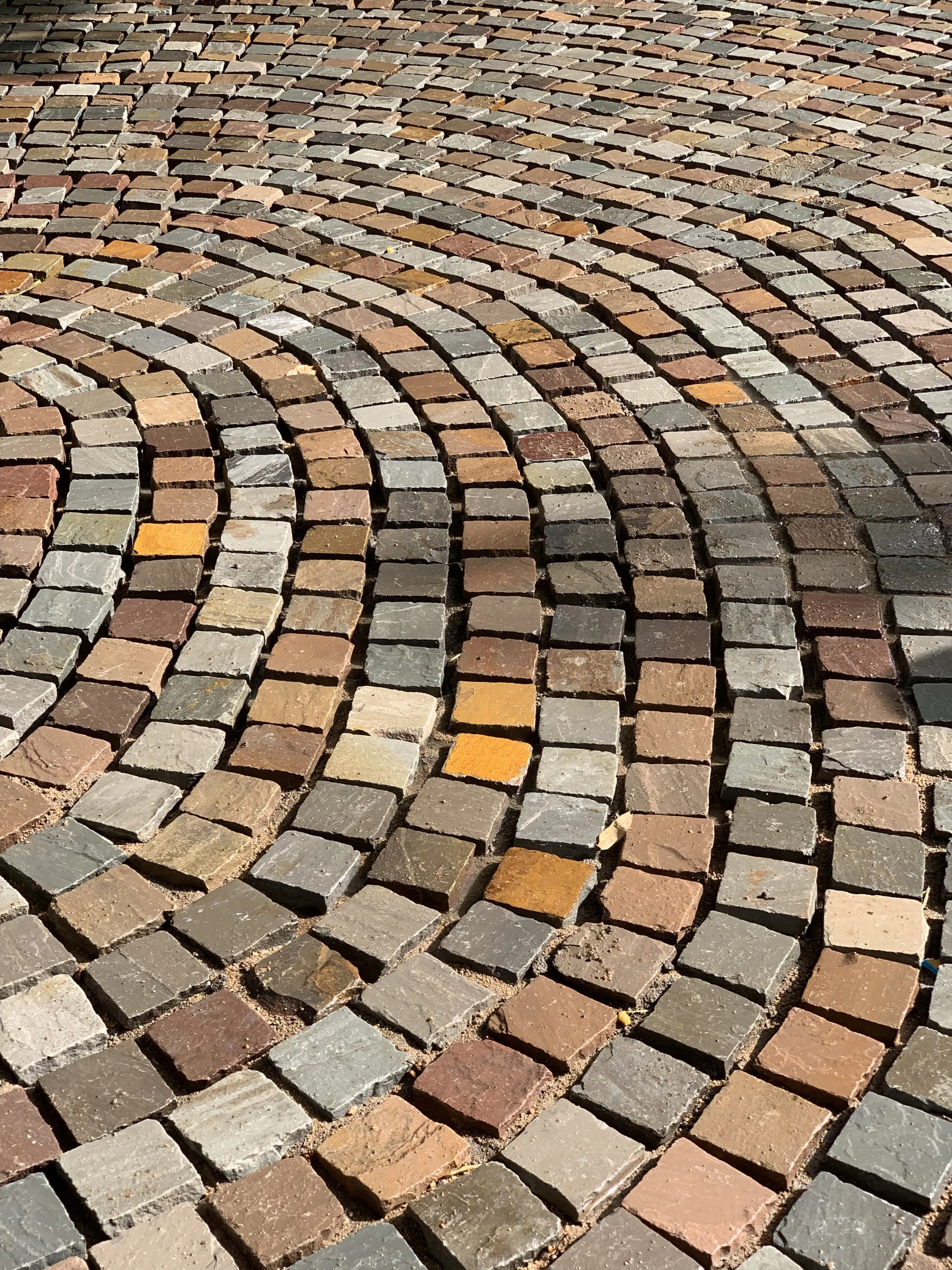 Radial stone cobblestone paving patterns hand-laid in earthy multi-tonal hues