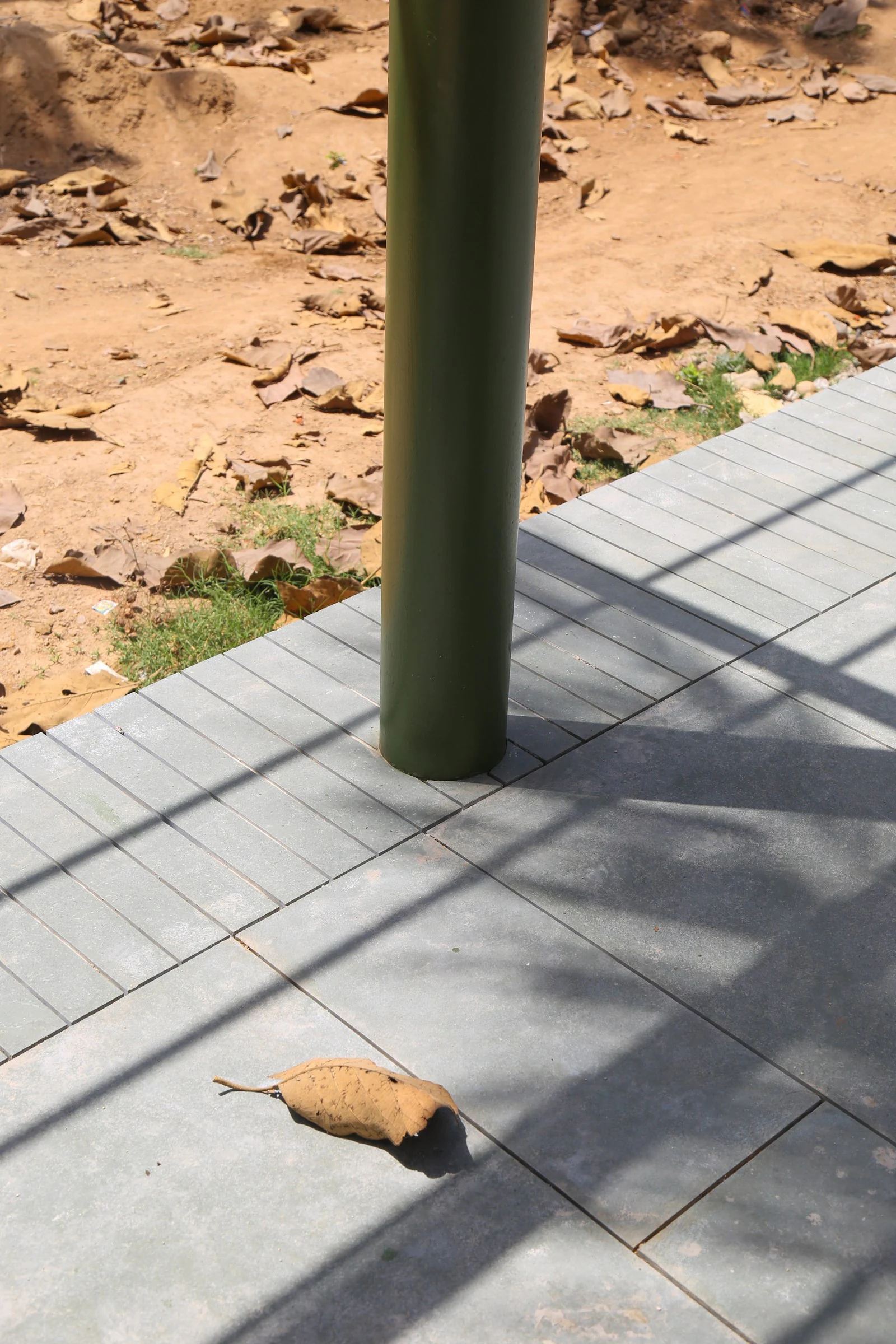 Steel column anchored upon precision-laid natural stone paving slabs