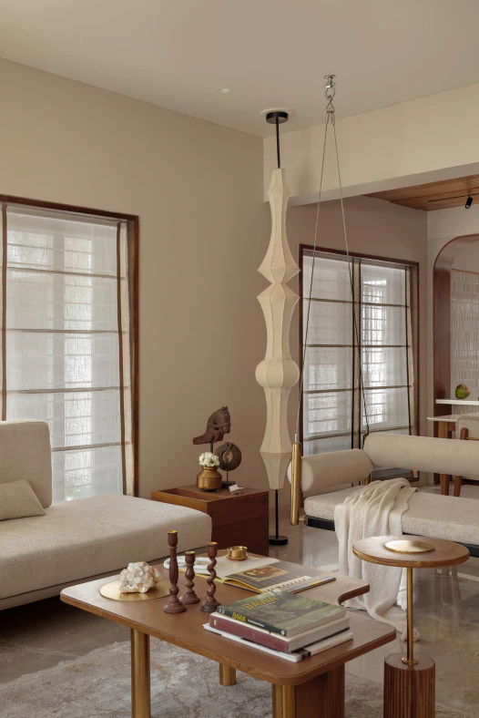 Suspended upholstered indoor swing with brass rods and a tall sculptural fabric floor lamp in the living room