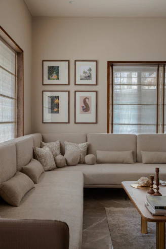 Living room corner showing plush cream sectional sofa, embroidered throw cushions, and framed botanical prints