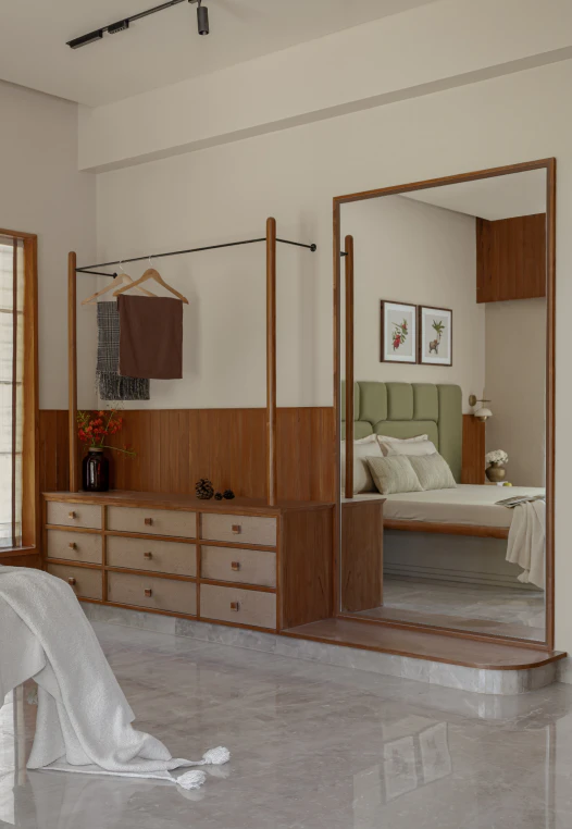 Bedroom dressing nook with open clothes hanging rack, woven-front drawer credenza, and full-height mirror